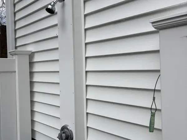 Bright clean white vinyl siding around outdoor shower after professional soft wash in Franklin MA