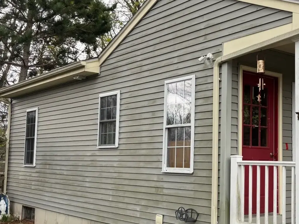 Gray vinyl siding with green algae and mildew stains before house washing in Franklin MA