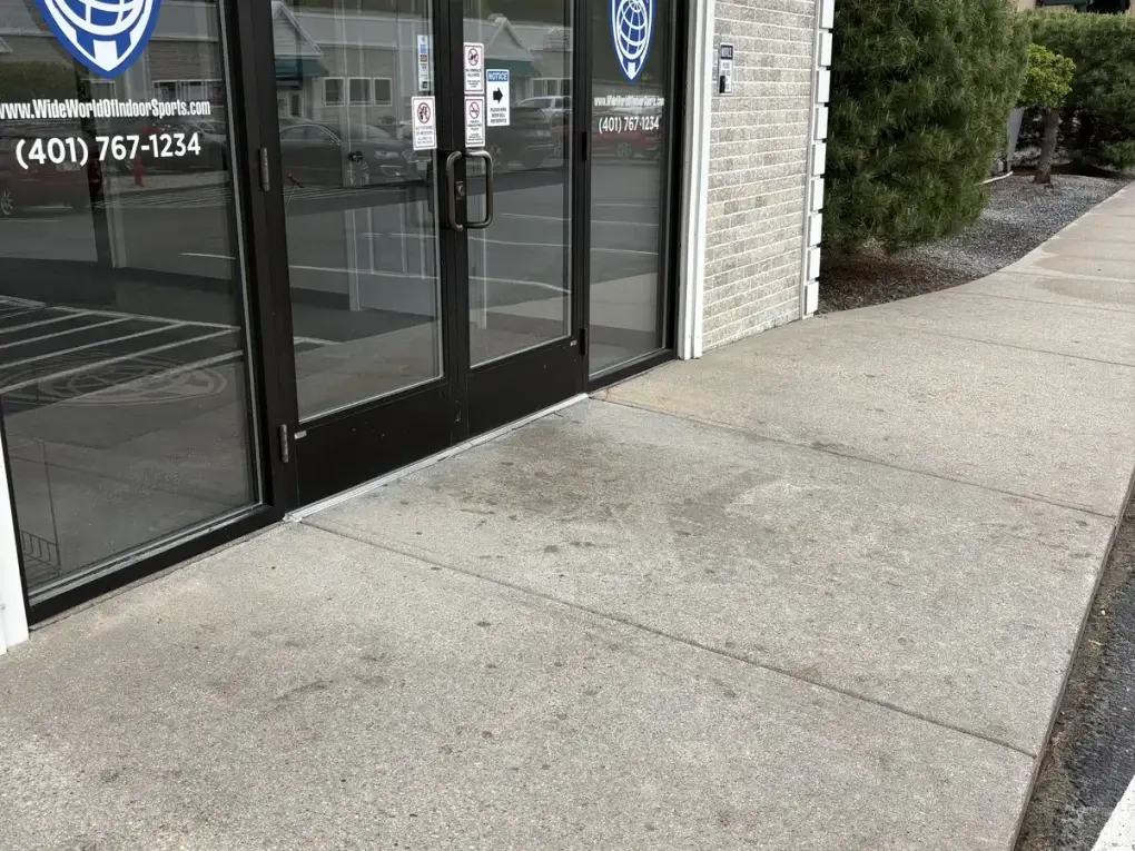 Storefront sidewalk after professional gum stain removal and pressure washing, showing a clean concrete entryway