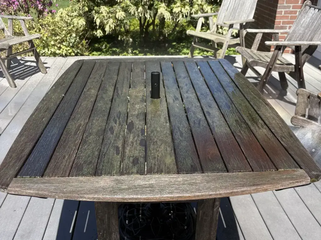 Dark weathered outdoor deck table with mold and mildew before cleaning