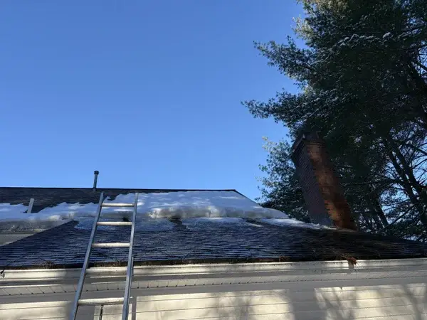 Residential roof cleared of snow showing shingles after ice dam service