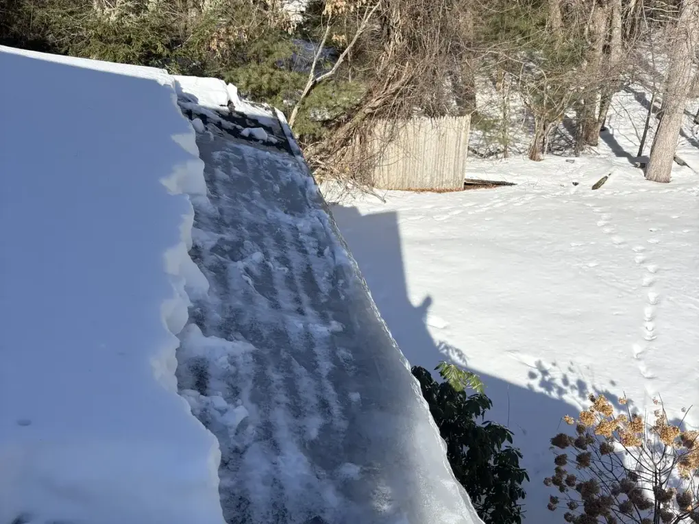 Roof covered in snow and ice dam buildup before professional removal