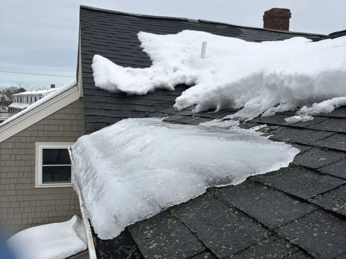 Roof edge with thick ice dam and snow buildup