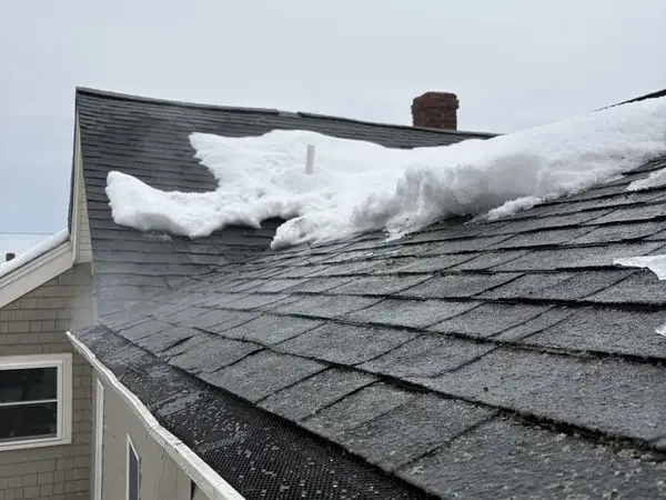 Roof edge cleared of ice dam - clean gutters and shingles visible