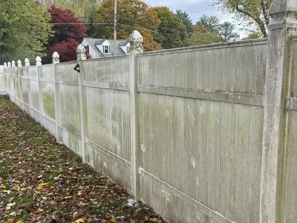 Dirty vinyl fence with green algae and mildew stains before cleaning
