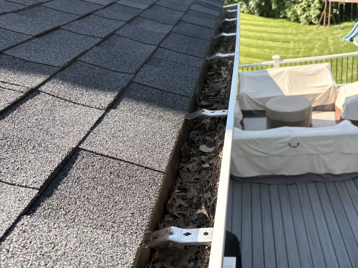 Gutter in Uxbridge MA packed with leaves and debris before professional cleaning