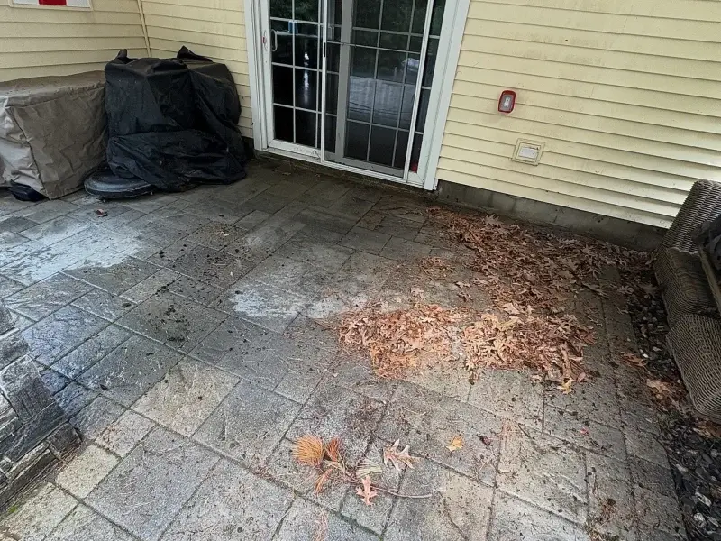 Paver patio covered with leaves and debris before cleaning