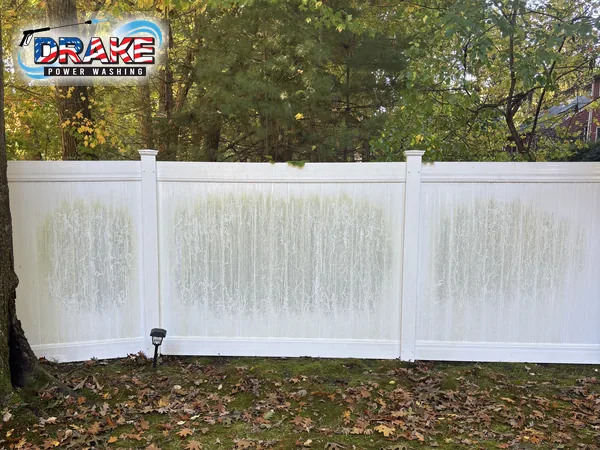 White vinyl fence with green organic staining before fence cleaning in Franklin MA
