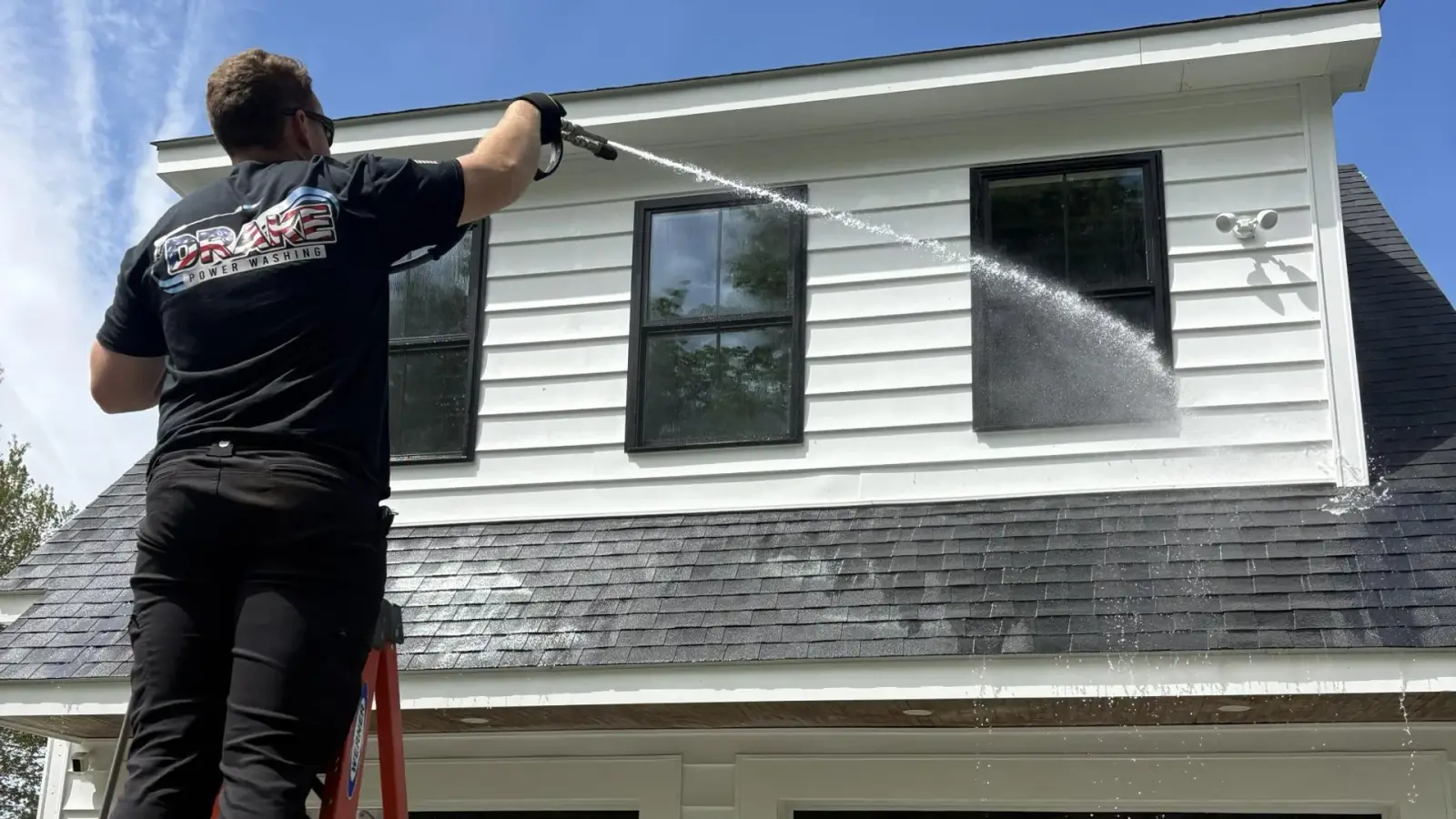 Shane Drake soft-washing a roof on a ladder in MetroWest Massachusetts