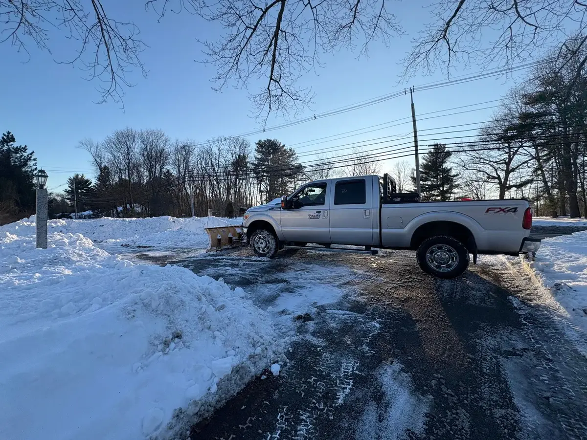 Drake Power Washing FX4 plow truck clearing snow from a driveway during the day